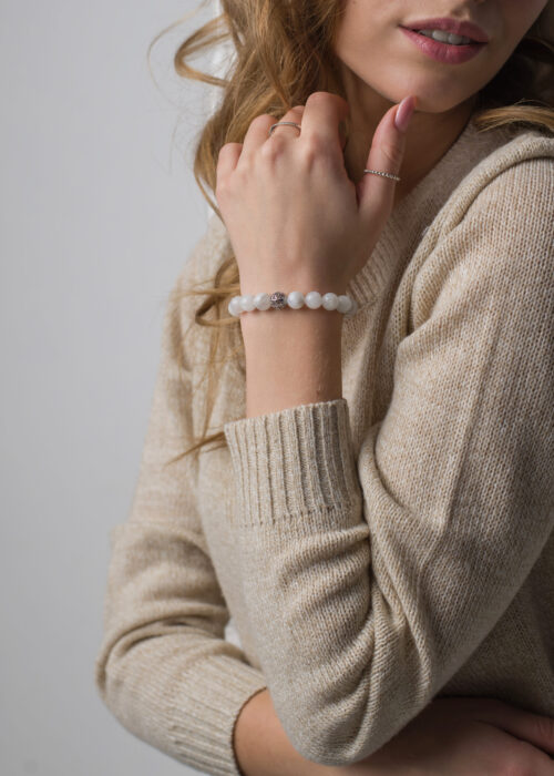 bracelet made of moonstoneis on the hand, on the arm is a bracelet made of white stones, girl on white background